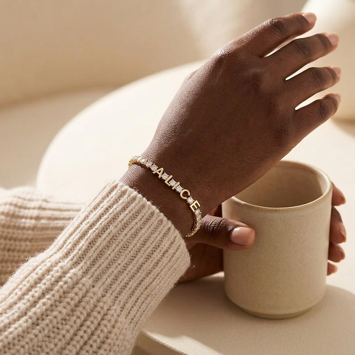 Bracelet prénom doré porté au poignet avec une tasse