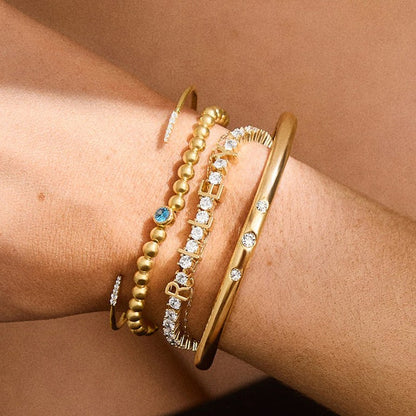 Bracelet tennis prénom accumulé avec des joncs dorés